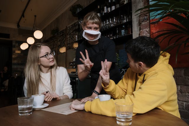 man-in-yellow-hoodie-jacket-ordering-to-a-waitress-through-sign-language experiencing a Short Term Accommodation adventure.